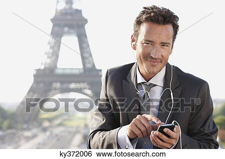 Businessman using a mobile phone with the Eiffel Tower in the background, Paris, Ile-de-France, France View Large Photo Image Stock Photograph - Businessman using a mobile phone with the Eiffel Tower in the background, Paris, Ile-de-France, France. Fotosearch