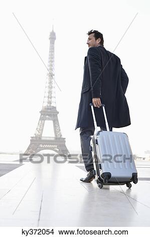 Businessman walking with luggage with the Eiffel Tower in the background, Paris, Ile-de-France, France View Large Photo Image Picture - Businessman walking with luggage with the Eiffel Tower in the background, Paris, Ile-de-France, France. Fotosearch