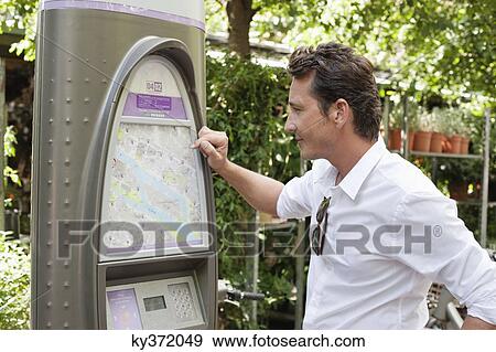 Stock Photo - Man looking a map in a ticket machine, Paris, Ile-de-France, France. Fotosearch