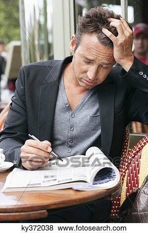 Stock Photo - Man reading a magazine looking worried, Paris, Ile-de-France, France. Fotosearch