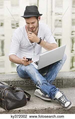 Man sitting on the ledge of a canal and talking on a mobile phone, Paris, Ile-de-France, France View Large Photo Image Stock Image - Man sitting on the ledge of a canal and talking on a mobile phone, Paris, Ile-de-France, France. Fotosearch