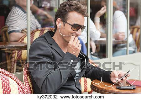 Stock Image - Man talking on a mobile phone in a restaurant, Paris, Ile-de-France, France. Fotosearch