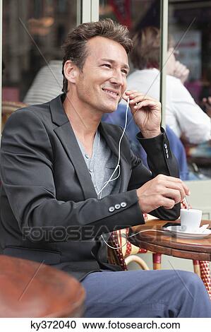 Stock Image - Man talking on a mobile phone in a restaurant, Paris, Ile-de-France, France. Fotosearch