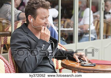 Stock Image - Man talking on a mobile phone in a restaurant, Paris, Ile-de-France, France. Fotosearch