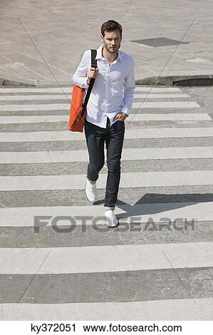 Stock Image - Man walking on crosswalk, Paris, Ile-de-France, France. Fotosearch