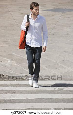 Stock Photo - Man walking on crosswalk, Paris, Ile-de-France, France. Fotosearch