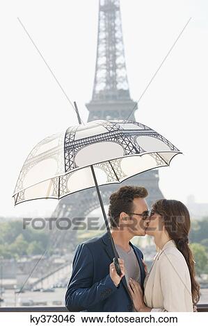 Couple kissing under an umbrella with the Eiffel Tower in the background, Paris, Ile-de-France, France View Large Photo Image Stock Photograph - Couple kissing under an umbrella with the Eiffel Tower in the background, Paris, Ile-de-France, France. Fotosearch
