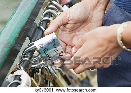 Couple locking a padlock of love on a bridge, Pont des Arts, Paris, Ile-de-France, France View Large Photo Image Stock Image - Couple locking a padlock of love on a bridge, Pont des Arts, Paris, Ile-de-France, France. Fotosearch
