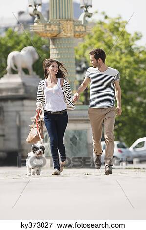 Stock Photo - Couple running with a puppy, Paris, Ile-de-France, France. Fotosearch
