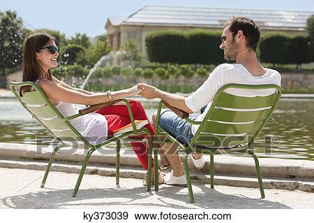 Stock Photo - Couple sitting in chairs near a pond, Bassin octogonal, Jardin des Tuileries, Paris, Ile-de-France, France. Fotosearch