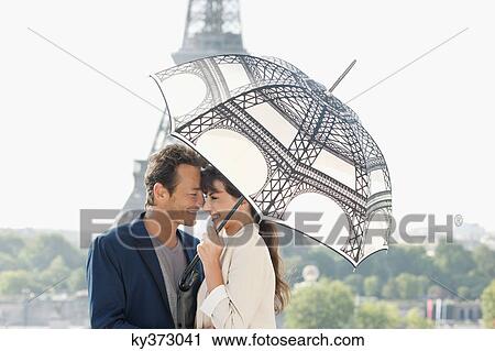 Couple under an umbrella with the Eiffel Tower in the background, Paris, Ile-de-France, France View Large Photo Image Stock Image - Couple under an umbrella with the Eiffel Tower in the background, Paris, Ile-de-France, France. Fotosearch