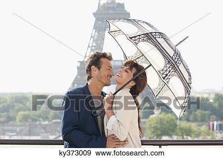 Stock Photo - Couple under an umbrella with the Eiffel Tower in the background, Paris, Ile-de-France, France. Fotosearch