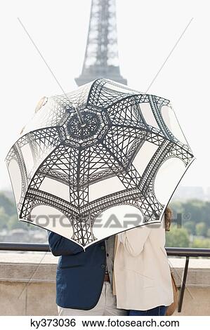 Stock Photograph - Couple under an umbrella with the Eiffel Tower in the background, Paris, Ile-de-France, France. Fotosearch
