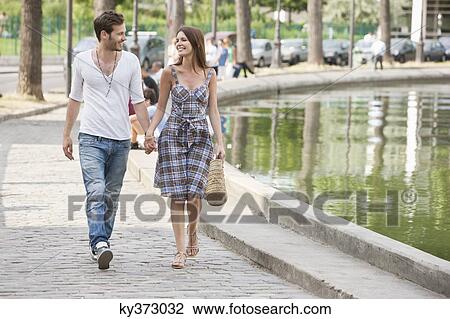 Stock Image - Couple walking near a canal and smiling, Paris, Ile-de-France, France. Fotosearch
