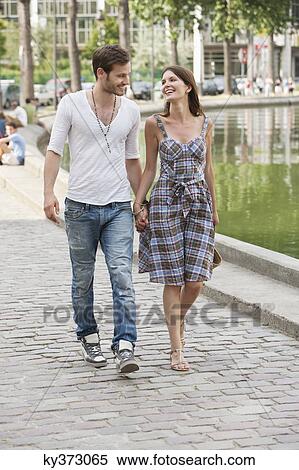 Stock Photography - Couple walking near a canal and smiling, Paris, Ile-de-France, France. Fotosearch