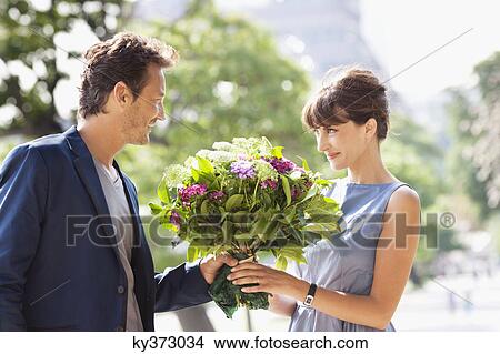 Man giving a bouquet of flowers to a woman with the Eiffel Tower in the background, Paris, Ile-de-France, France View Large Photo Image Picture - Man giving a bouquet of flowers to a woman with the Eiffel Tower in the background, Paris, Ile-de-France, France. Fotosearch