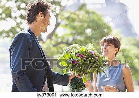 Man giving a bouquet of flowers to a woman with the Eiffel Tower in the background, Paris, Ile-de-France, France View Large Photo Image Stock Image - Man giving a bouquet of flowers to a woman with the Eiffel Tower in the background, Paris, Ile-de-France, France. Fotosearch