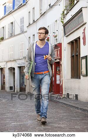 Stock Photo - Man carrying a file while eating food, Paris, Ile-de-France, France. Fotosearch