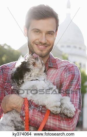 Picture - Man carrying a puppy, Paris, Ile-de-France, France. Fotosearch