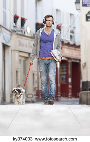 Stock Image - Man holding a dog on leash, Paris, Ile-de-France, France. Fotosearch