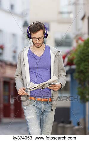 Stock Image - Man reading a newspaper on the street, Paris, Ile-de-France, France. Fotosearch
