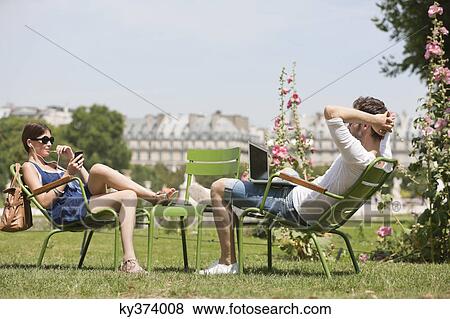 Man using a laptop with a woman talking on a mobile phone, Jardin des Tuileries, Paris, Ile-de-France, France View Large Photo Image Stock Photo - Man using a laptop with a woman talking on a mobile phone, Jardin des Tuileries, Paris, Ile-de-France, France. Fotosearch