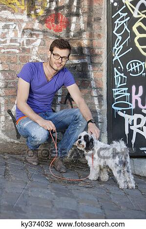 Man with a puppy in front of a graffiti wall, Paris, Ile-de-France, France View Large Photo Image Stock Image - Man with a puppy in front of a graffiti wall, Paris, Ile-de-France, France. Fotosearch