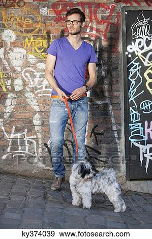 Man with a puppy in front of a graffiti wall, Paris, Ile-de-France, France View Large Photo Image Stock Photo - Man with a puppy in front of a graffiti wall, Paris, Ile-de-France, France. Fotosearch