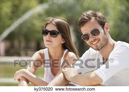 Stock Image - Couple sitting in a garden, Bassin octogonal, Jardin des Tuileries, Paris, Ile-de-France, France. Fotosearch