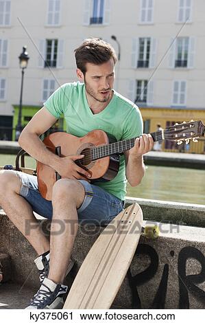Stock Image - Man playing a guitar, Canal St Martin, Paris, Ile-de-France, France. Fotosearch