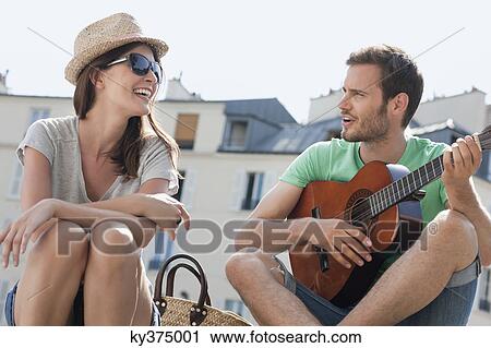 Man playing a guitar with a woman smiling, Canal St Martin, Paris, Ile-de-France, France View Large Photo Image Stock Image - Man playing a guitar with a woman smiling, Canal St Martin, Paris, Ile-de-France, France. Fotosearch