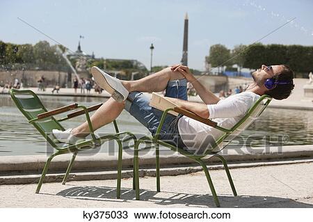 Man reclining in a chair and listening to music, Bassin octogonal, Jardin des Tuileries, Paris, Ile-de-France, France View Large Photo Image Stock Image - Man reclining in a chair and listening to music, Bassin octogonal, Jardin des Tuileries, Paris, Ile-de-France, France. Fotosearch