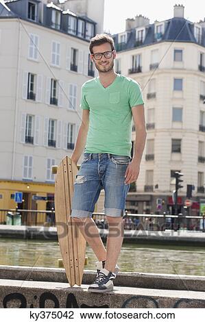 Man standing on the ledge of a canal with a skateboard, Canal St Martin, Paris, Ile-de-France, France View Large Photo Image Stock Image - Man standing on the ledge of a canal with a skateboard, Canal St Martin, Paris, Ile-de-France, France. Fotosearch