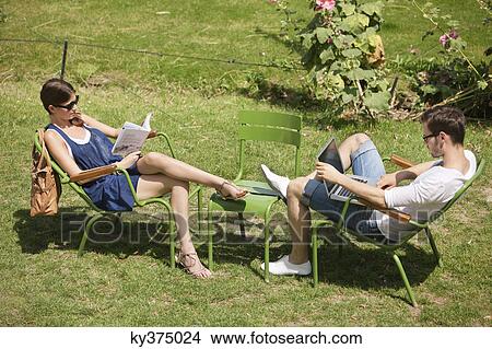 Man using a laptop with a woman reading a magazine in garden, Jardin des Tuileries, Paris, Ile-de-France, France View Large Photo Image Picture - Man using a laptop with a woman reading a magazine in garden, Jardin des Tuileries, Paris, Ile-de-France, France. Fotosearch