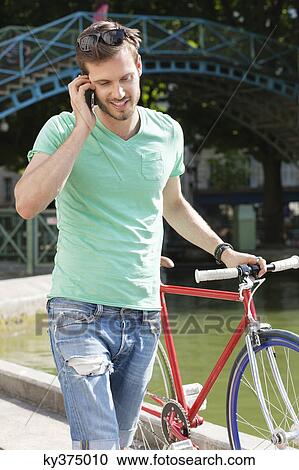 Man walking with a bicycle and talking on a mobile phone, Paris, Ile-de-France, France View Large Photo Image Stock Image - Man walking with a bicycle and talking on a mobile phone, Paris, Ile-de-France, France. Fotosearch