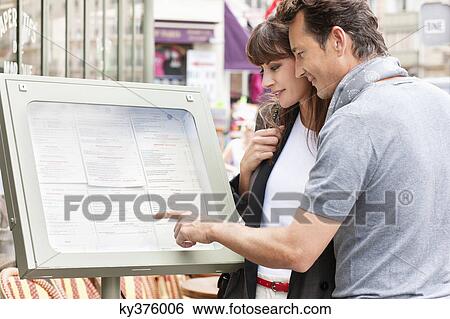 Stock Photograph - Couple reading menu at a restaurant, Paris, Ile-de-France, France. Fotosearch