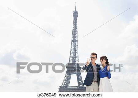Couple showing victory sign with the Eiffel Tower in the background, Paris, Ile-de-France, France View Large Photo Image Stock Photo - Couple showing victory sign with the Eiffel Tower in the background, Paris, Ile-de-France, France. Fotosearch