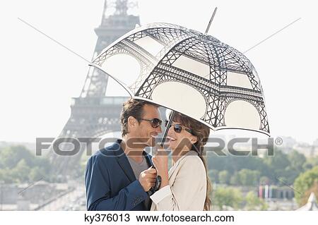 Couple under an umbrella with the Eiffel Tower in the background, Paris, Ile-de-France, France View Large Photo Image Stock Image - Couple under an umbrella with the Eiffel Tower in the background, Paris, Ile-de-France, France. Fotosearch