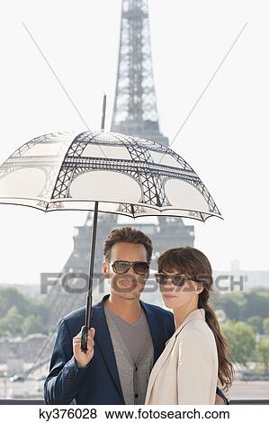 Couple under an umbrella with the Eiffel Tower in the background, Paris, Ile-de-France, France View Large Photo Image Stock Photo - Couple under an umbrella with the Eiffel Tower in the background, Paris, Ile-de-France, France. Fotosearch