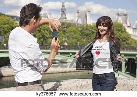 Man taking a picture of a woman with a mobile phone, Seine River, Paris, Ile-de-France, France View Large Photo Image Stock Photo - Man taking a picture of a woman with a mobile phone, Seine River, Paris, Ile-de-France, France. Fotosearch