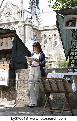 Stock Photo - Woman reading a book at a book stall, Notre Dame de Paris, Paris, Ile-de-France, France. Fotosearch