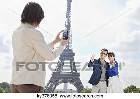 Woman taking a picture of couple with the Eiffel Tower in the background, Paris, Ile-de-France, France View Large Photo Image Stock Photo - Woman taking a picture of couple with the Eiffel Tower in the background, Paris, Ile-de-France, France. Fotosearch