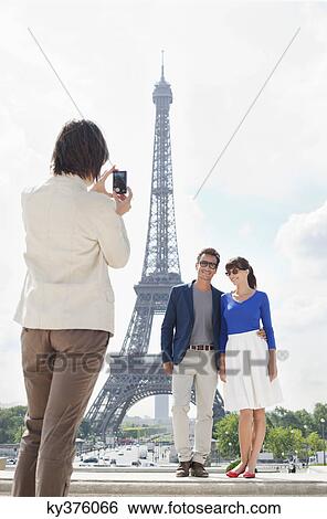 Woman taking a picture of couple with the Eiffel Tower in the background, Paris, Ile-de-France, France View Large Photo Image Stock Photograph - Woman taking a picture of couple with the Eiffel Tower in the background, Paris, Ile-de-France, France. Fotosearch