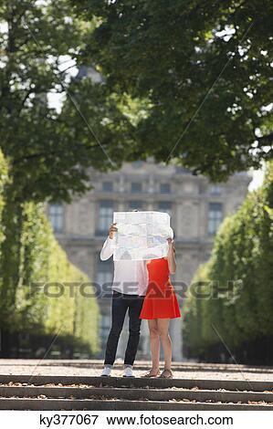 Stock Photo - Couple holding a map in front of their faces, Terrasse De l'Orangerie, Jardin des Tuileries, Paris, Ile-de-France, France. Fotosearch