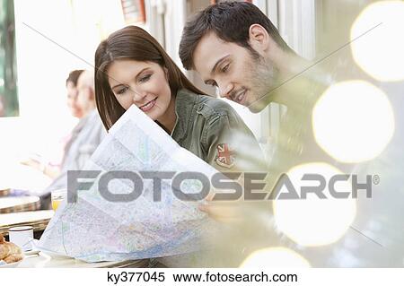 Stock Photography - Couple sitting at a sidewalk cafe and reading a map, Paris, Ile-de-France, France. Fotosearch