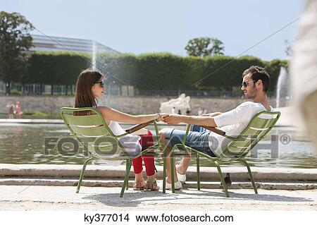Picture - Couple sitting in chairs near a pond, Bassin octogonal, Jardin des Tuileries, Paris, Ile-de-France, France. Fotosearch