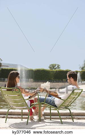 Stock Photograph - Couple sitting in chairs near a pond, Bassin octogonal, Jardin des Tuileries, Paris, Ile-de-France, France. Fotosearch