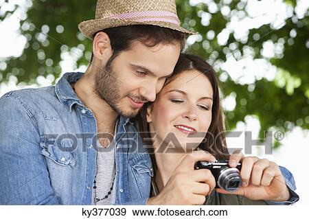 Stock Photo - Couple watching photos in a digital camera, Paris, Ile-de-France, France. Fotosearch