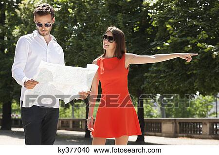 Stock Image - Man reading a map with a woman pointing, Terrasse De l'Orangerie, Jardin des Tuileries, Paris, Ile-de-France, France. Fotosearch