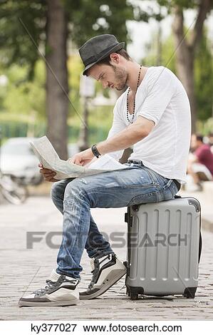 Man sitting on the suitcase and reading a map, Paris, Ile-de-France, France View Large Photo Image Stock Photo - Man sitting on the suitcase and reading a map, Paris, Ile-de-France, France. Fotosearch